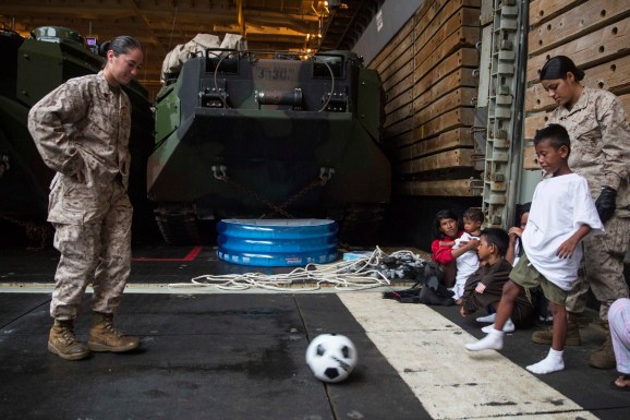 U.S. Marines with the 15th Marine Expeditionary Unit play soccer with an Indonesia child while he waits to be transported to an Indonesian coast guard vessel from the USS Rushmore (LSD 47), June 11, 2015. The child, along with 64 other distressed mariners were rescued from a sinking craft in the waters between the Indonesian islands of Kalimantan and Sulawesi. (U.S. Marine Corps photo by Sgt. Emmanuel Ramos/Released)